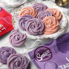 purple and pink frosted cupcakes sitting on a plate next to a bar of chocolate