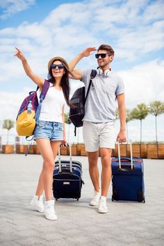 the man and woman are walking with their suitcases in front of them, both pointing at something