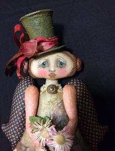 a small doll with a green hat holding flowers