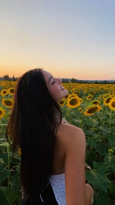 a woman standing in the middle of a field of sunflowers with her eyes closed