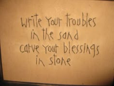 a sign with writing written on it that says write your troubles in the sand cave your blessing is in stone