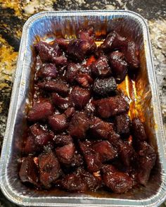 a tin pan filled with meat sitting on top of a granite counter next to a knife