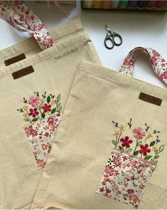 two bags with flowers on them sitting next to scissors