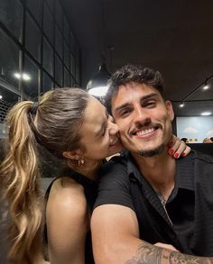 a man and woman sitting next to each other in front of a mirror with their faces close together