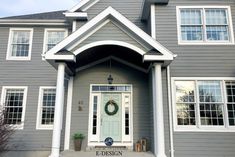 a gray house with white trim and wreath on the front door is featured in this image