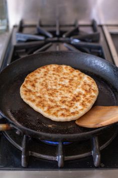 a pancake is cooking on the stove with a wooden spatula in front of it