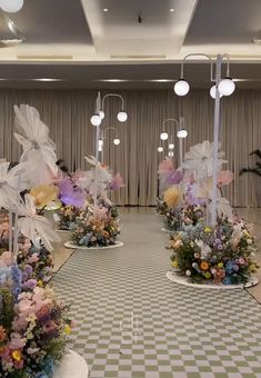 several flower arrangements are arranged on pedestals in the middle of a room with checkered flooring