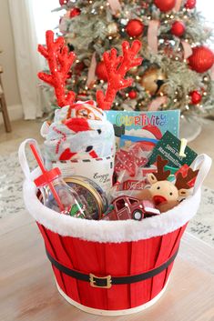 a basket filled with christmas items in front of a christmas tree