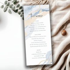 the menu card is laying on top of a blanket next to an olive branch and other items