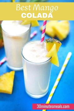 two glasses filled with ice cream next to pineapples and strawberries on a blue table