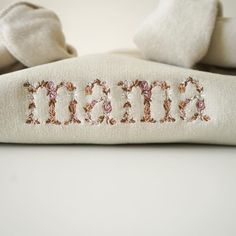 the word mama spelled with sequins on top of a white pillow and blanket