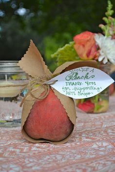 an apple sitting on top of a table next to a jar filled with flowers and candles