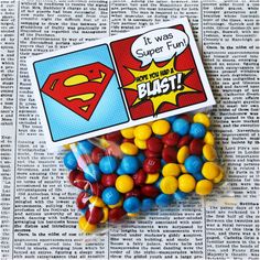 some candy is in the shape of a superman logo and it's on top of a newspaper