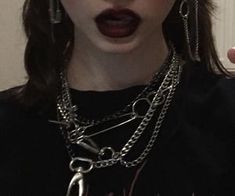 a woman with black lipstick and chains on her neck holding a cell phone up to her ear