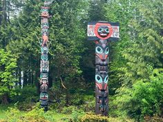 two totems in the woods with trees behind them