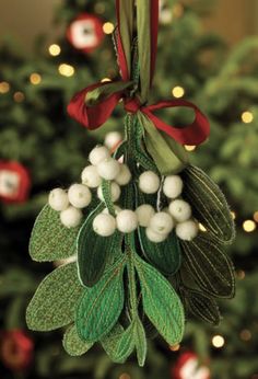 a christmas ornament hanging from a tree with berries and leaves attached to it