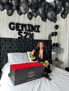 a woman sitting on top of a bed next to a box filled with red roses