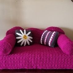 a crocheted couch with two pillows on it and a clock in the background