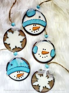 three decorated cookies with snowmen on them sitting on a white furnishing surface