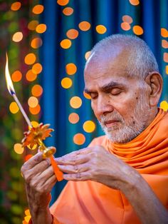 an old man holding a candle and looking at it with bright lights in the background