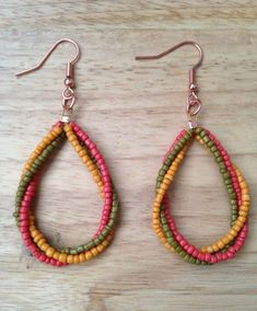 two pairs of colorful beaded earrings sitting on top of a wooden table