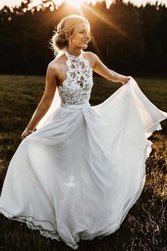 a woman in a white dress is walking through the grass