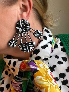 a close up of a person wearing large earring designs on their ears and neck