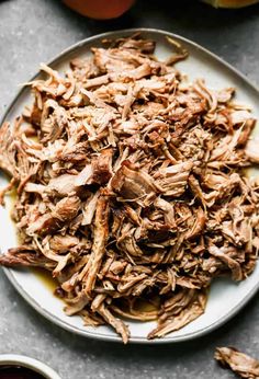 shredded meat on a white plate next to apples