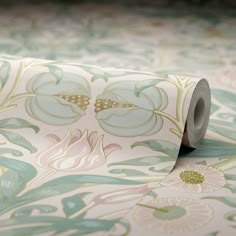 a roll of toilet paper sitting on top of a floral print wallpaper covered in green and pink flowers