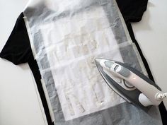 an iron is sitting on top of a piece of paper next to a t - shirt