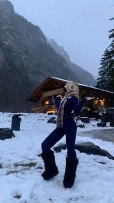 a person standing in the snow with skis on their head and one hand up