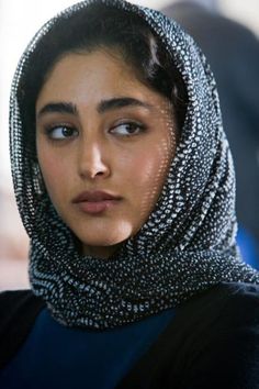 a woman wearing a head scarf and looking at the camera with an intense look on her face