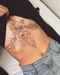 a woman's stomach with a flower tattoo on the side and an intricate design