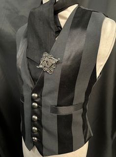 "3 items include :- waistcoat, cravat and hand crafted pin. This is a stunning black heavy suiting fabric waist coat.It is fully lined .It has wide stripes. It has  pockets and adjustable back  . It has gunmetal  buttons. It comes with a black cravat and hand crafted metal pin .  Available in two sizes:- M chest 40\" L chest 44\"  Adjustable waist . High quality well made Makes a stunning steampunk gentleman's outfit! Thank you for looking" Party Vest With Buttons In Black, Black Party Vest With Buttons, Elegant Pinstripe Vest For Formal Occasions, Steampunk Formal Sleeveless Vest, Formal Steampunk Sleeveless Vest, Gothic Black Vest For Costume Party, Formal Sleeveless Steampunk Vest, Steampunk Black Vest For Costume Party, Black Steampunk Vest For Costume Party