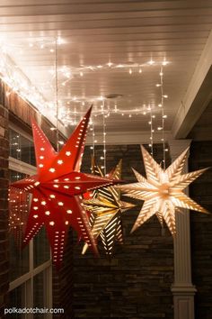 some lights are hanging from the ceiling in front of a brick wall and two star decorations