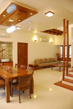 a dining room table and chairs in front of a living room with stairs leading up to the second floor