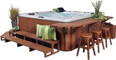 an outdoor hot tub with stools next to it and plants on the table top