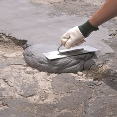 a person is using a knife to cut into a piece of cement on the ground