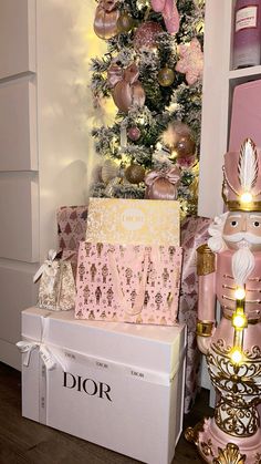 a christmas tree with pink and gold decorations in front of it, next to presents