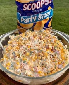 an image of a bowl of party size corn chows on the grass with a bag of chips in the background