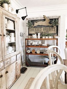 an old fashioned kitchen with white walls and wood furniture, including a wooden cabinet filled with dishes