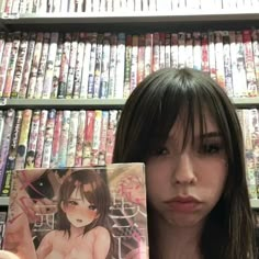 a woman holding up a cd in front of a shelf full of dvd's