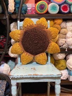 a stuffed sunflower sitting on top of a wooden chair in front of yarns