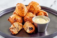 a plate topped with muffins next to a small cup of cream cheese sauce