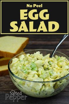 an egg salad in a glass bowl next to slices of bread