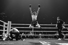 a man standing on top of a boxing ring holding his hands up in the air