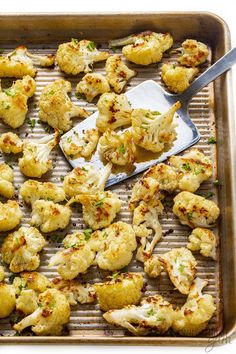 roasted cauliflower on a baking sheet with a spatula and spoon in it