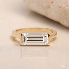 a gold ring with an emerald cut diamond