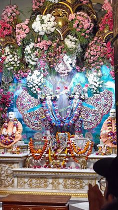 an idol with flowers and garlands on it in front of a man made statue