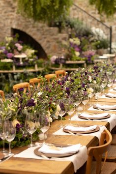 a long table is set with flowers and place settings for an outdoor dinner party or celebration